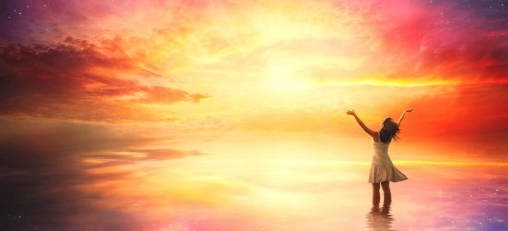 woman with arms open to a beautiful sunset sky